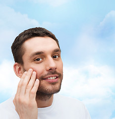 Image showing beautiful smiling man touching his face