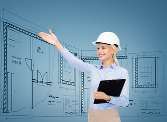 Image showing smiling businesswoman in helmet with clipboard