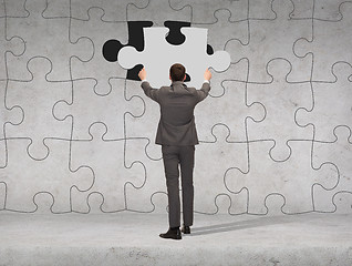 Image showing businessman in suit setting piece of puzzle