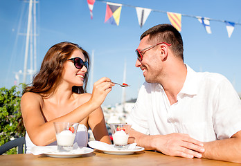 Image showing smiling couple eating dessert at cafe