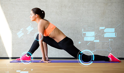 Image showing smiling woman stretching leg on mat in gym