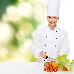 Image showing smiling female chef chopping vegetables