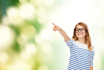 Image showing cute little girl in eyeglasses pointing in the air