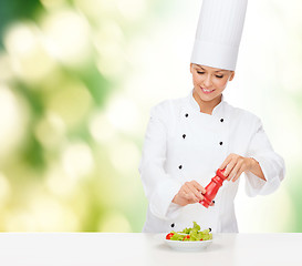 Image showing smiling female chef with preparing salad