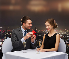 Image showing excited young woman looking at boyfriend with box