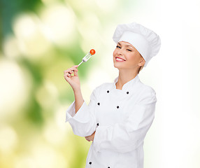 Image showing smiling female chef with fork and tomato