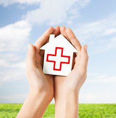 Image showing hands holding paper house with red cross