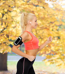 Image showing sporty woman running with smartphone and earphones