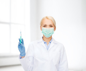 Image showing doctor in mask holding syringe with injection