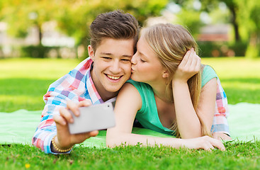Image showing smiling couple making selfie and kissing in park