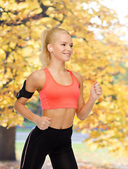 Image showing sporty woman running with smartphone and earphones