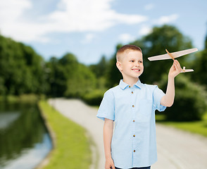 Image showing smiling little boy holding a wooden airplane model