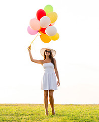 Image showing smiling young woman in sunglasses with balloons