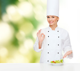 Image showing smiling female chef with salad on plate