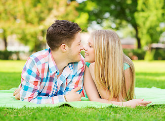 Image showing smiling couple lying on blanket in park