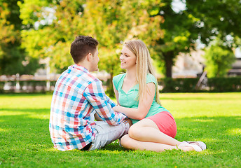 Image showing smiling couple sitting on grass in park