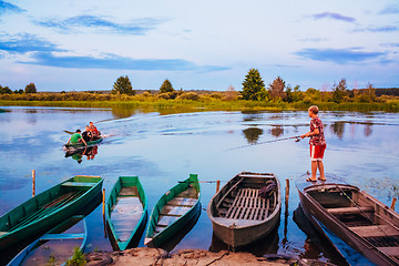 Image showing Belarusian Boy Fishing From Old Boats At Sunset Of A Summer Day