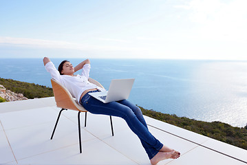 Image showing relaxed young woman at home working on laptop