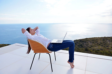 Image showing relaxed young woman at home working on laptop