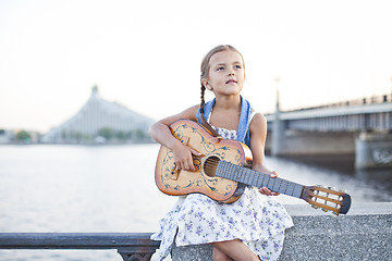 Image showing Girl playing guitar on river embankment
