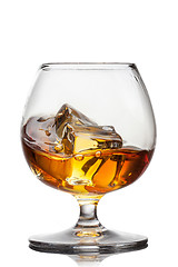 Image showing Splash of whiskey with ice in glass isolated