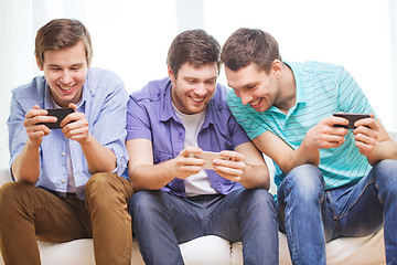 Image showing smiling friends with smartphones at home