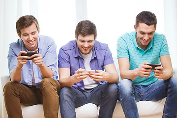 Image showing smiling friends with smartphones at home