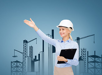 Image showing smiling businesswoman in helmet with clipboard