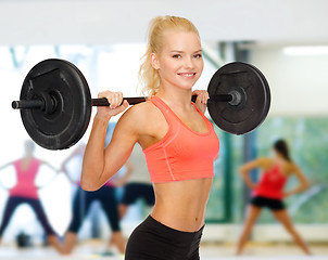 Image showing smiling sporty woman exercising with barbell