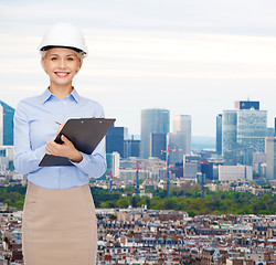 Image showing smiling businesswoman in helmet with clipboard