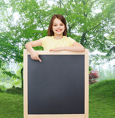 Image showing happy little girl pointing finger to blackboard