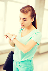 Image showing surprised student girl looking at wristwatch