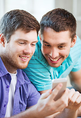 Image showing smiling friends with smartphone at home