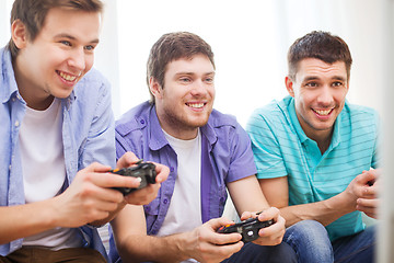 Image showing smiling friends playing video games at home