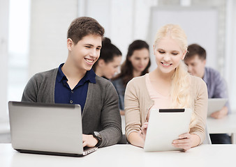 Image showing two smiling students with laptop and tablet pc