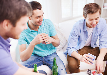Image showing smiling male friends playing cards at home