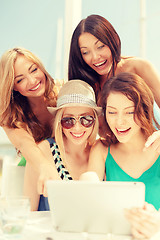 Image showing smiling girls looking at tablet pc in cafe