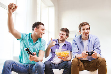 Image showing smiling friends playing video games at home