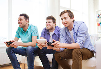 Image showing smiling friends playing video games at home