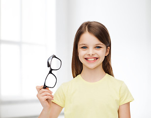 Image showing smiling cute little girl holding black eyeglasses