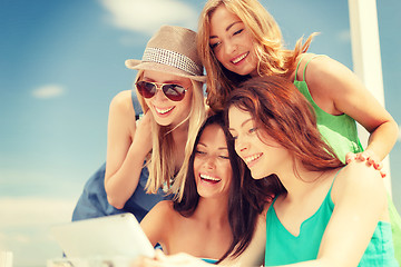 Image showing smiling girls looking at tablet pc in cafe