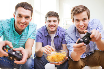 Image showing smiling friends playing video games at home