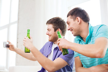 Image showing smiling friends with smartphone and beer at home