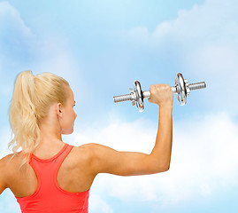 Image showing sporty woman with heavy steel dumbbell from back