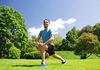 Image showing smiling man stretching outdoors