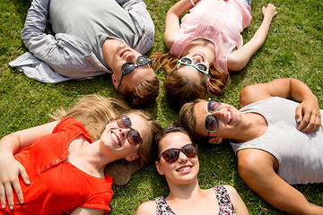 Image showing group of smiling friends lying on grass outdoors