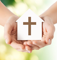 Image showing close up of hands and paper house with cross