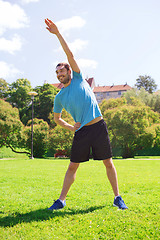 Image showing smiling man stretching outdoors