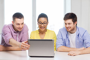 Image showing three smiling colleagues with laptop in office