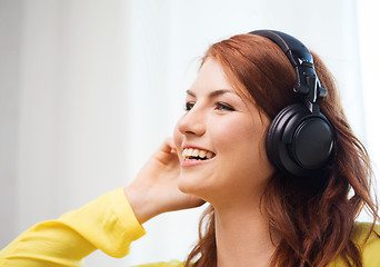 Image showing smiling young girl in headphones at home